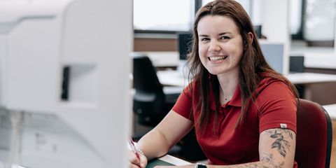 Häring.Auszubildende sitzt lachend am PC