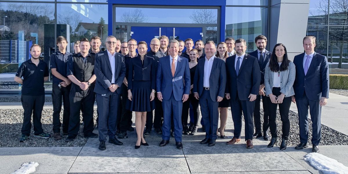 Geschäftsleitung von Häring steht mit dem Gouverneubesuch und den Mitarbeiter vor dem Gebäude von Häring und lächeln in die Kamera