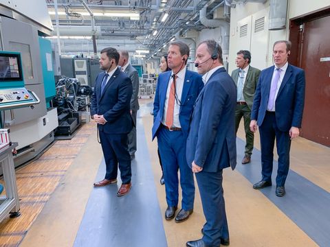 Geschäftsleitung von Häring mit dem Besuch von Gouverneu in der Produktionshalle, alle tragen ein Kopfhörer