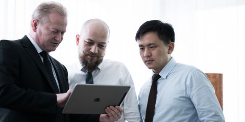 drei Mitarbeiter Häring Projektmanager besprechen mit Tablet Hintergrund hell unscharf 