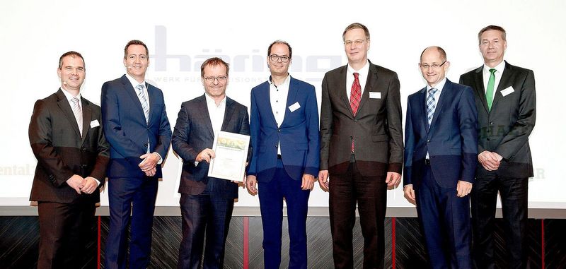 Geschäftsleitung von Häring stehen auf der Bühne mit weiteren männlichen Personen und bekommen eine Verleihung eines Schäffler-Award