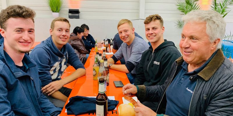 Mitarbeiter von Häring sitzen auf Bierbänken und schauen zur Kamera