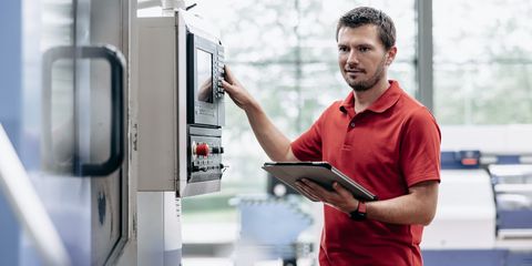 männlicher Auszubildende steht an Maschine in der Akademie